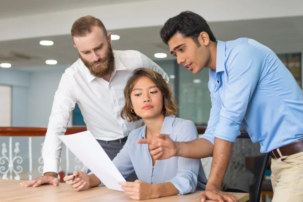 Foto de un grupo de profesionales en una oficina, discutiendo un plan de trabajo. Proyecta confianza, experiencia y colaboración, representando al equipo de asesores listos para ayudar.